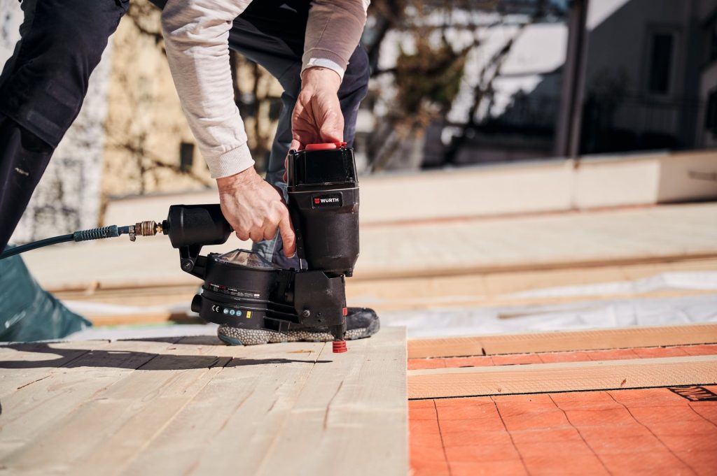 Handwerker verwendet einen Druckluftnagler auf einer Baustelle zur Holzverarbeitung. Befestigung von Holzbretter.