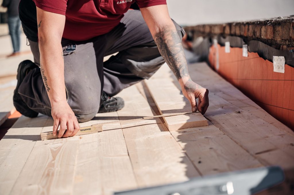 Handwerker misst fachmännisch Holzbretter auf einer Baustelle.