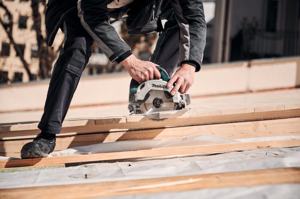 Handwerker schneidet Holz mit einer Kreissäge auf einer Baustelle, um präzise Zuschnitte zu erstellen.