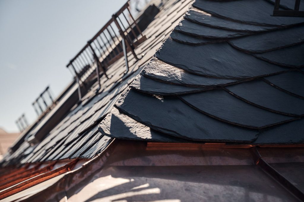 Nahaufnahme eines Schieferdachs mit Sonne, die die Struktur und Textur der Schieferplatten betont.